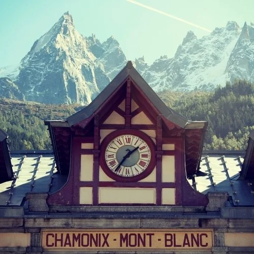 Façade de la gare de Chamonix-Mont-Blanc avec son horloge et les montagnes en arrière-plan.